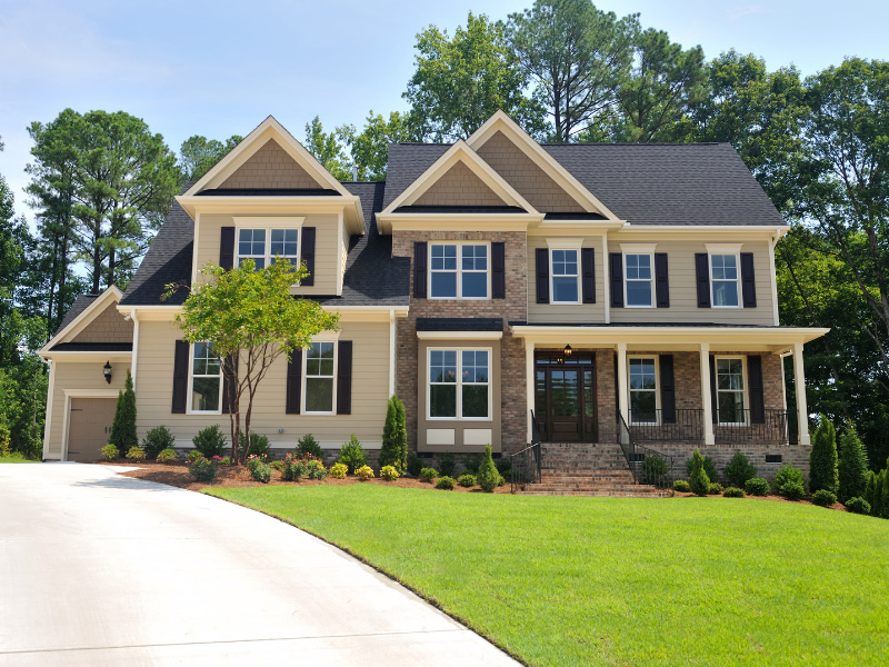 A two-storey suburban home with a front porch, green lawn and long driveway